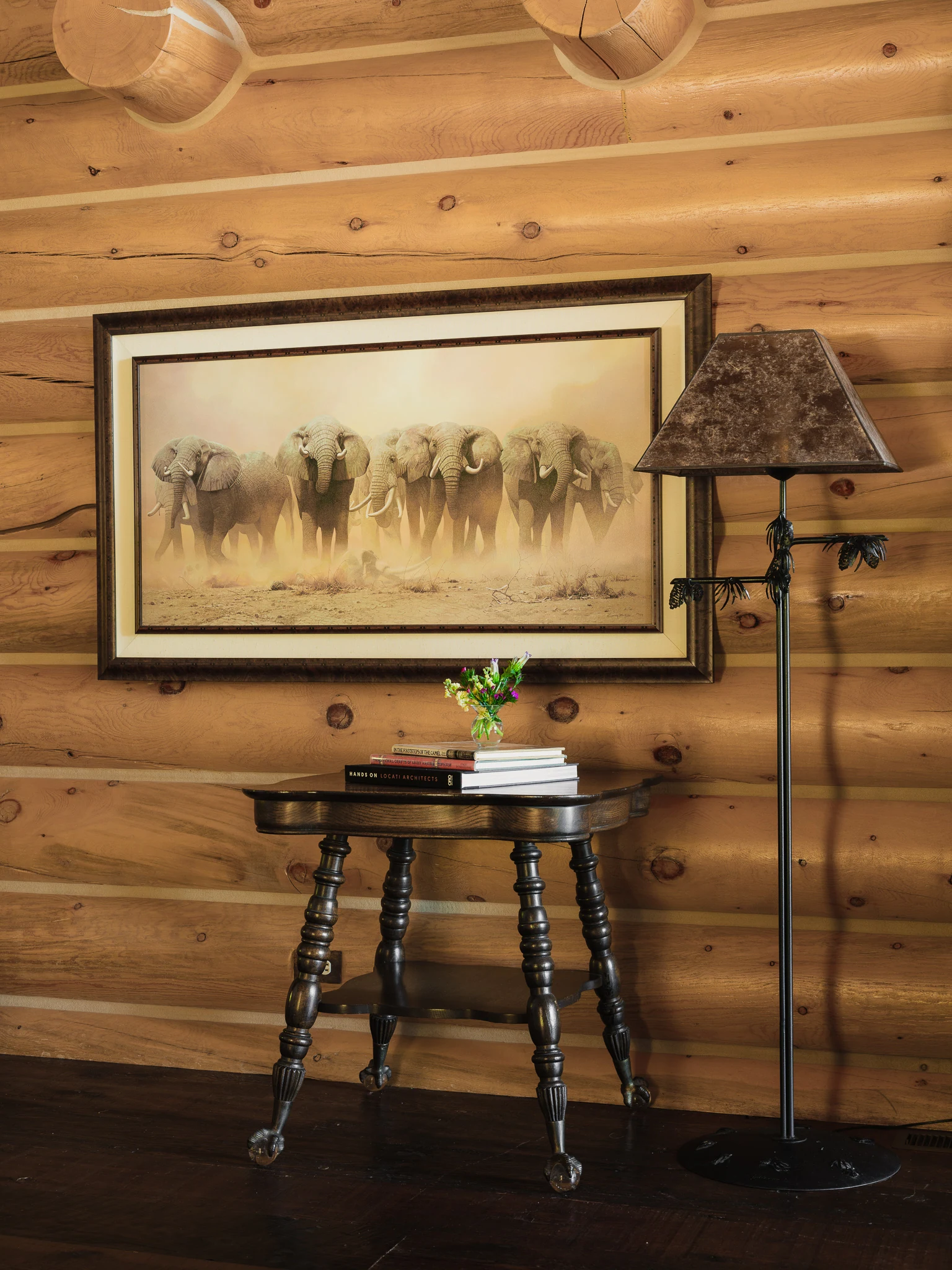 Console table styled with elephant artwork and a floor lamp against log walls — interior design photography Livingston Montana, Bear Canyon Ranch